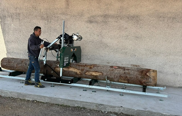 Artisan en train de scier une grume sur mesure dans son atelier